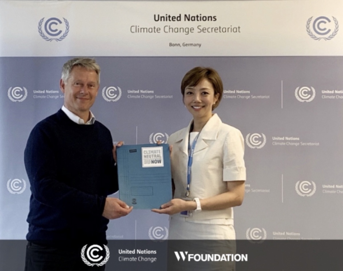 Youree Lee with a UNFCCC representative holding a Climate Neutral Now folder at the UN Climate Change secretariat in Bonn